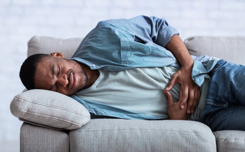 Un Africain Souffrant De Douleurs Abdominales Couché Sur Un Canapé à  L'intérieur Photo stock - Image du nourriture, maladie: 216618044