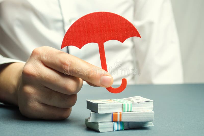 Un agente de seguro sostiene un paraguas rojo sobre billetes de dólar Protección de los ahorros Manteniendo el dinero seguro Inve