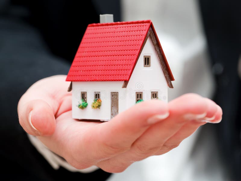 Un agente inmobiliario que sostiene una pequeña nueva casa en sus manos imagen de archivo libre de regalías Un agente inmobiliario que sostiene una pequeña nueva casa en sus manos imagen de archivo libre de regalías
