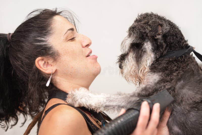 Un'amante della famiglia che abbracciava teneramente un cagnolino in un salone brontolone. Concetto di amore e cura per gli animal fotografia stock libera da diritti Un'amante della famiglia che abbracciava teneramente un cagnolino in un salone brontolone. Concetto di amore e cura per gli animal fotografia stock libera da diritti