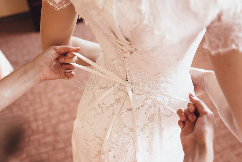Un'amica aiuta la sposa a merlettare il suo vestito da sposa immagini stock Un'amica aiuta la sposa a merlettare il suo vestito da sposa immagini stock