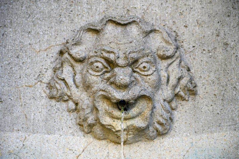 Un'antica faccia di pietra di una fontana immagini stock Un'antica faccia di pietra di una fontana immagini stock