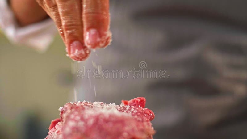 Un armario de un chef que añade especias a un trozo de carne almacen de metraje de vídeo