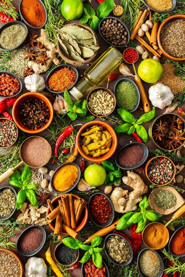 Un colorato assortimento di erbe aromatiche e spezie su uno sfondo marrone caldo, che mette in mostra la loro varietà visiva e fotografia stock