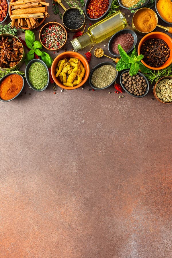 Un assortimento colorato di erbe aromatiche e spezie su uno sfondo marrone caldo che mostra la loro varietà visiva e fotografia stock