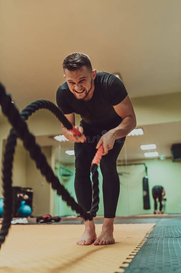 Un atleta che fa un intenso esercizio di corda da battaglia in palestra. immagine stock