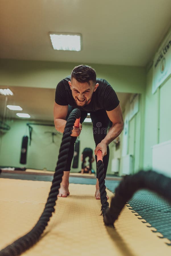 Un atleta che fa un intenso esercizio di corda da battaglia in palestra. immagini stock libere da diritti
