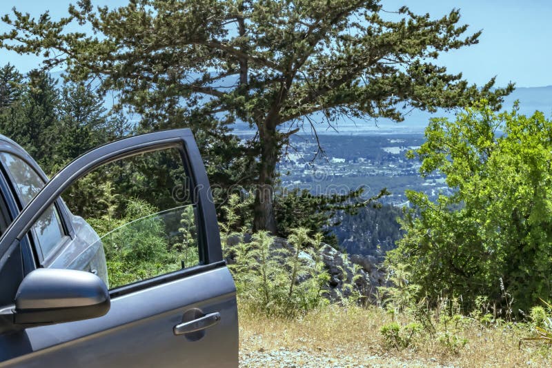 Un'automobile con una porta aperta sta su una collina o su una cima di una montagna con la vista sulla valle Priorit? bassa di pa fotografia stock Un'automobile con una porta aperta sta su una collina o su una cima di una montagna con la vista sulla valle Priorit? bassa di pa fotografia stock
