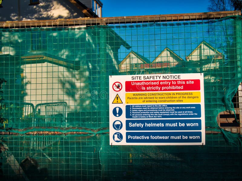 A brightly coloured construction / building site safety notice on the closed gate of an urban housing development in the UK, taken on a sunny day with a blue sky. A brightly coloured construction / building site safety notice on the closed gate of an urban housing development in the UK, taken on a sunny day with a blue sky.