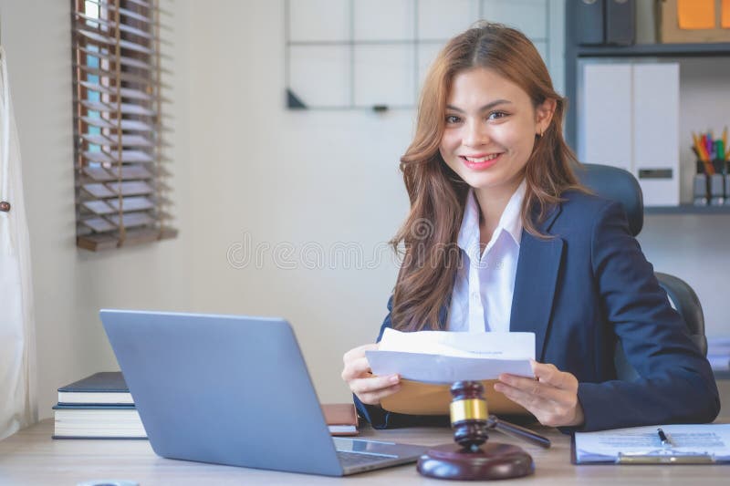Un avocat atrăgător și atrăgător, într-un costum negru, care să citească documente de caz unui client din birou cu un laptop royalty free stock images