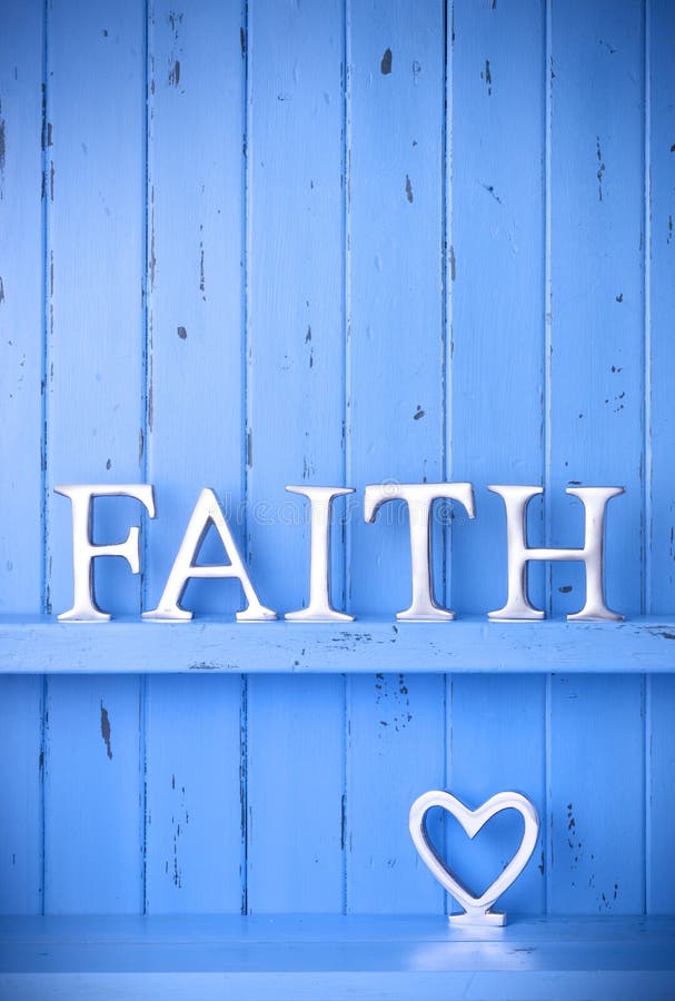 A rustic blue painted wood background with the word faith spelled out in metal letters and a love heart. A rustic blue painted wood background with the word faith spelled out in metal letters and a love heart.