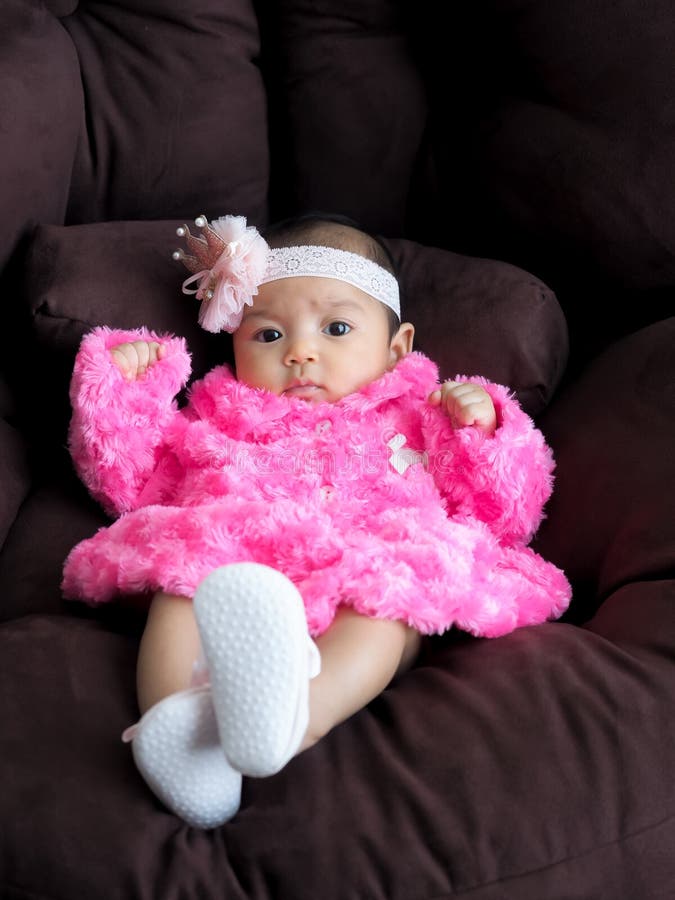 Un bambino asiatico della ragazza che porta una camicia rosa che si trova sul sofà con comodità fotografie stock libere da diritti Un bambino asiatico della ragazza che porta una camicia rosa che si trova sul sofà con comodità fotografie stock libere da diritti