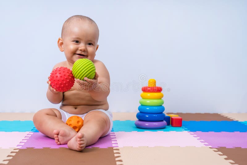 Un bambino gioca con palle di gomma per sviluppare abilità motorie manuali immagini stock libere da diritti