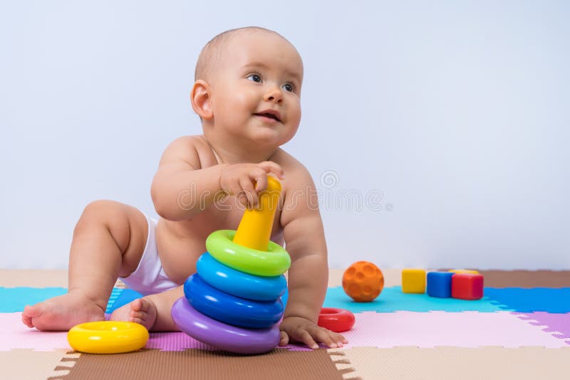 Un bambino gioca con una piramide multicolore di anelli. sviluppo del pensiero e delle abilità motorie manuali fotografia stock