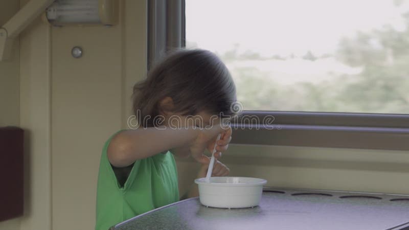 Un bambino mangia il pranzo seduto in uno scomparto del treno mentre viaggia