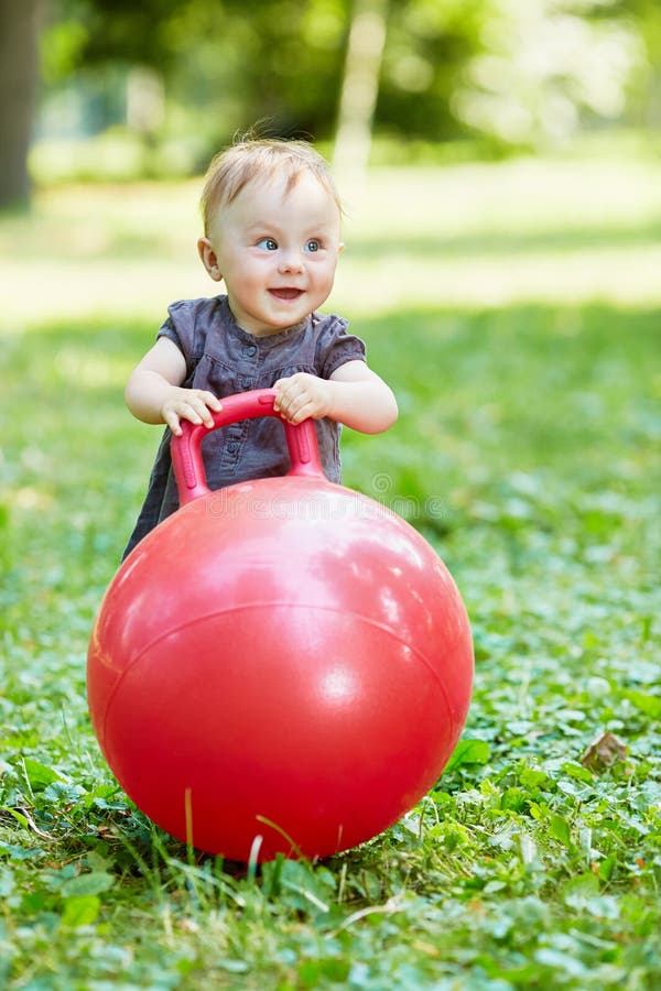 Un bambino sorridente gioca con la palla rossa per saltare su fotografie stock