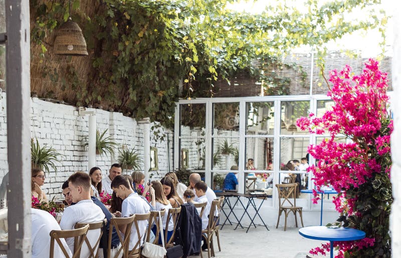 Un banchetto festoso all'aperto nel giardino. Eleganti ospiti al tavolo. Interno elegante e robusto. Uve sui muri e fiorenti fotografia stock libera da diritti