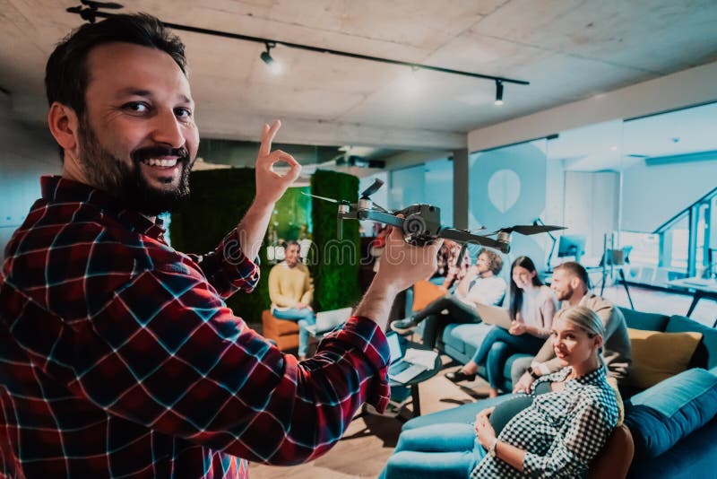 Un barbu dans un bureau moderne qui explique à sa jeune équipe diversifiée comment un drone travaille photo libre de droits