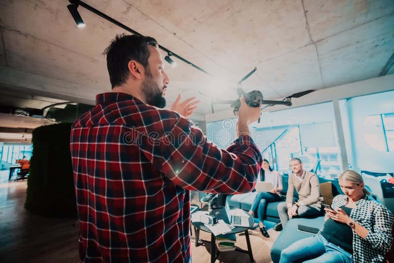 Un barbu dans un bureau moderne qui explique à sa jeune équipe diversifiée comment un drone travaille photographie stock