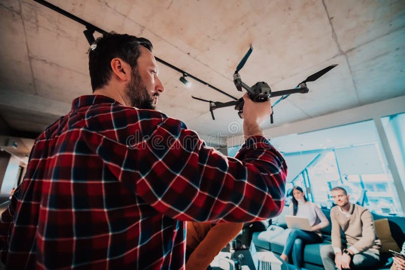Un barbu dans un bureau moderne qui explique à sa jeune équipe diversifiée comment un drone travaille photo libre de droits