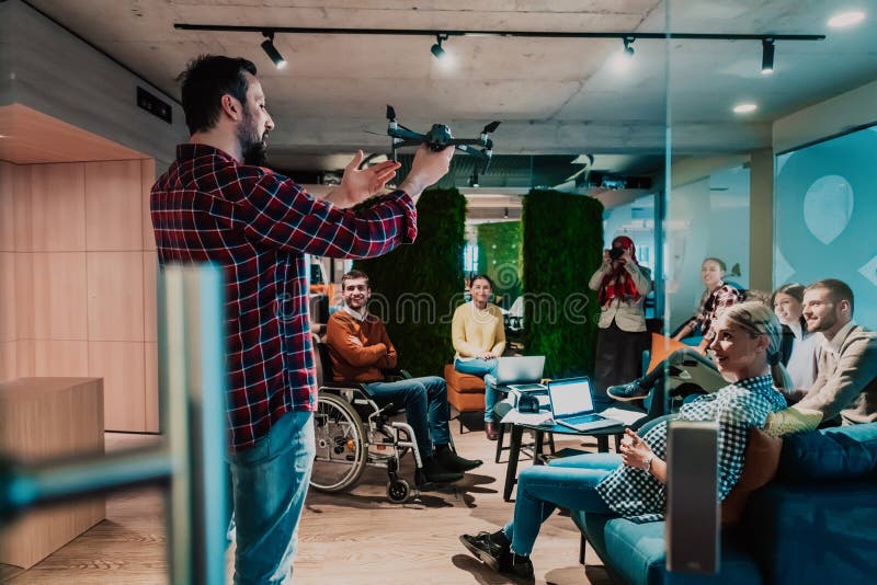 Un barbu dans un bureau moderne qui explique à sa jeune équipe diversifiée comment un drone travaille photos stock