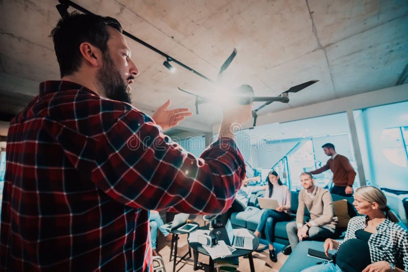 Un barbu dans un bureau moderne qui explique à sa jeune équipe diversifiée comment un drone travaille image libre de droits