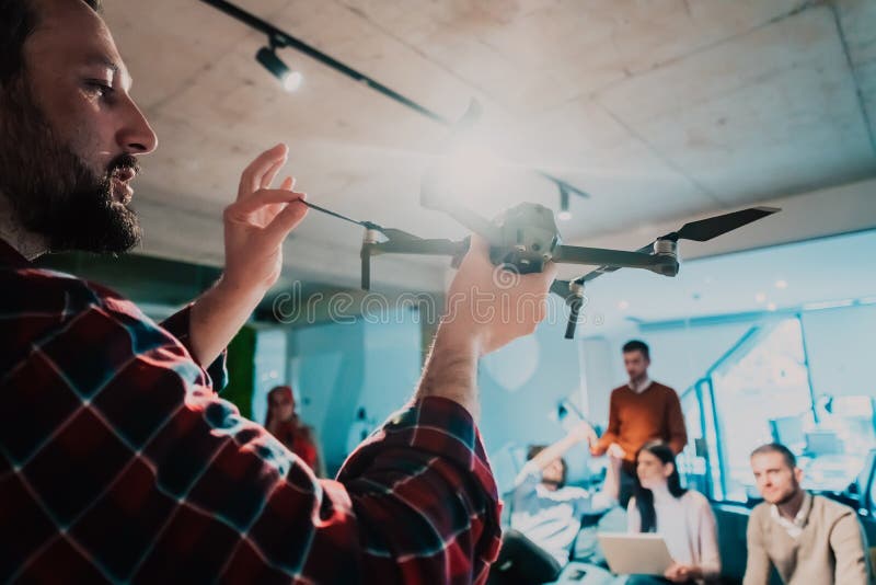 Un barbu dans un bureau moderne qui explique à sa jeune équipe diversifiée comment un drone travaille photos stock