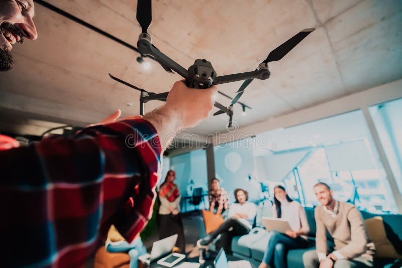 Un barbu dans un bureau moderne qui explique à sa jeune équipe diversifiée comment un drone travaille photos libres de droits