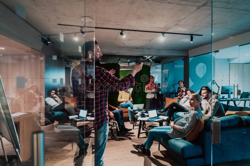 Un barbu dans un bureau moderne qui explique à sa jeune équipe diversifiée comment un drone travaille photo stock