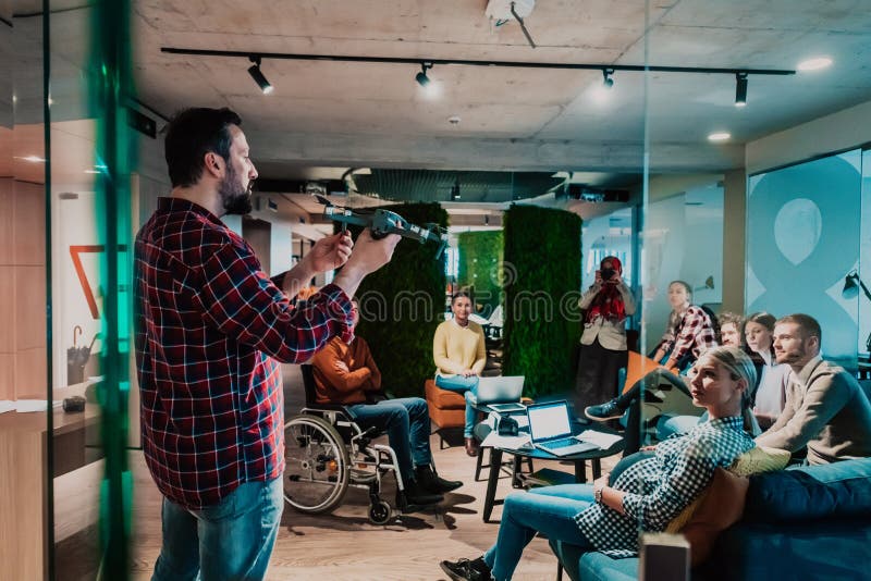 Un barbu dans un bureau moderne qui explique à sa jeune équipe diversifiée comment un drone travaille image stock