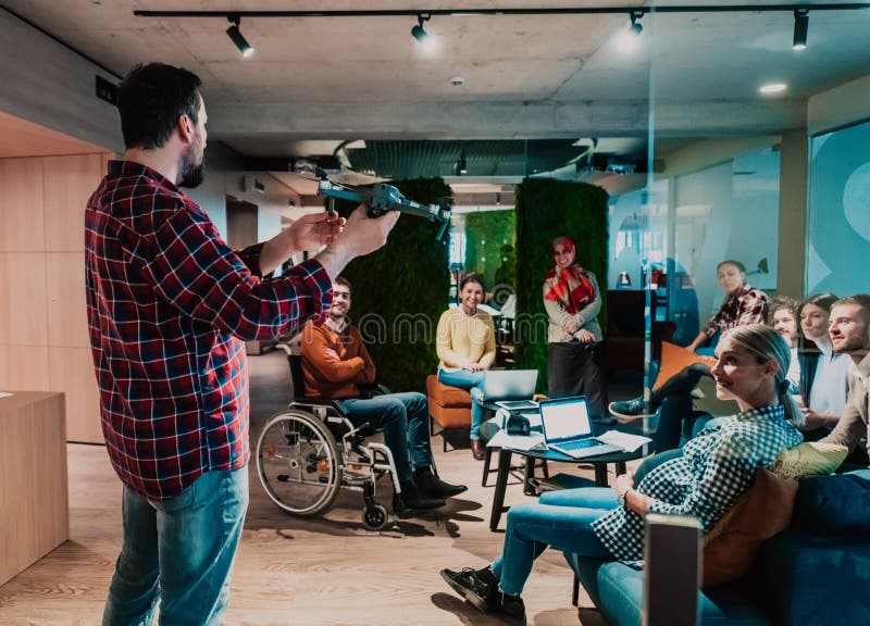 Un barbu dans un bureau moderne qui explique à sa jeune équipe diversifiée comment un drone travaille photographie stock