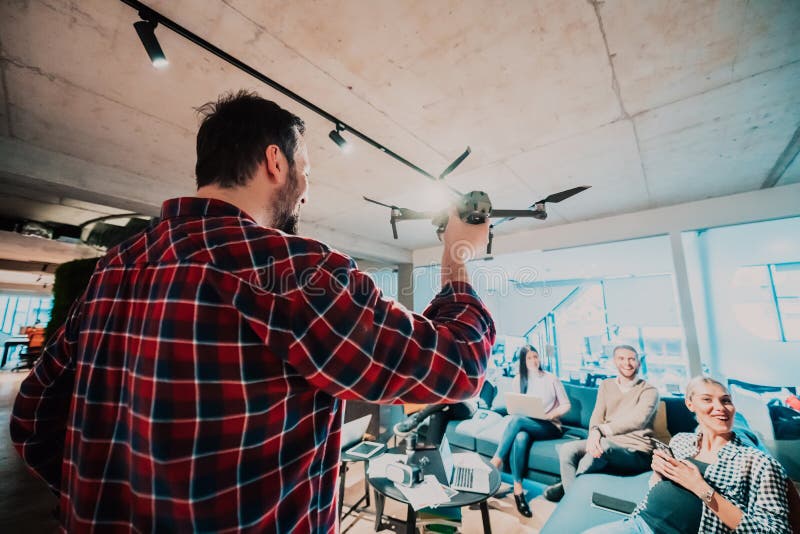 Un barbu dans un bureau moderne qui explique à sa jeune équipe diversifiée comment un drone travaille photographie stock