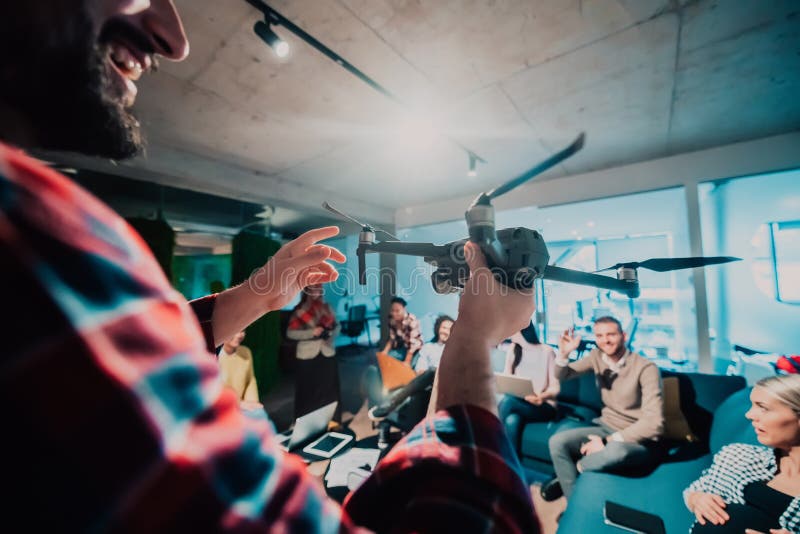 Un barbu dans un bureau moderne qui explique à sa jeune équipe diversifiée comment un drone travaille photo libre de droits