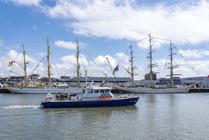 Un barco de policía moderno pasa el Tallships Mircea y Shabab Omán II, en el puerto de Scheveningen durante la vela en Schevening imágenes de archivo libres de regalías Un barco de policía moderno pasa el Tallships Mircea y Shabab Omán II, en el puerto de Scheveningen durante la vela en Schevening imágenes de archivo libres de regalías