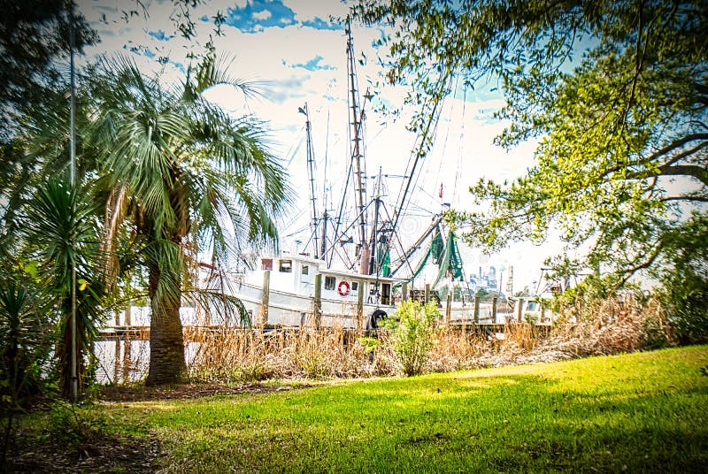 A shrimp boat moored at a small dock behind a house in Georgetown, SC on a cloudy day. A shrimp boat moored at a small dock behind a house in Georgetown, SC on a cloudy day.