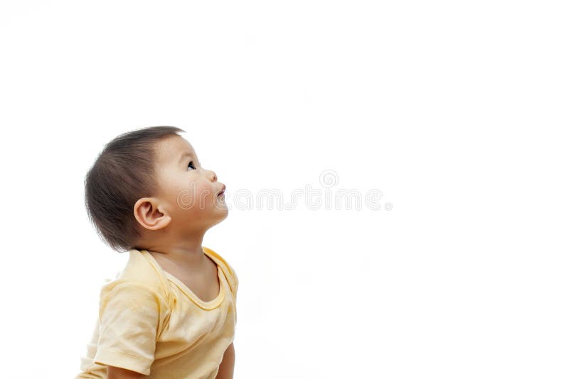 A baby girl with yellow clothes is looking up to the left side, not looking at the camera, turning her head to the left side. A baby girl with yellow clothes is looking up to the left side, not looking at the camera, turning her head to the left side