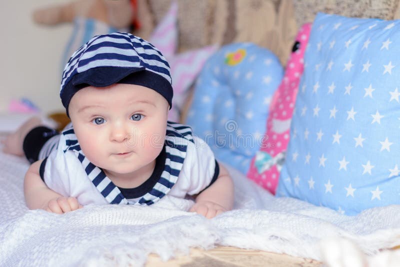 Un bello ragazzino in un marinaio del costume mette su un letto vicino ai cuscini fotografia stock libera da diritti Un bello ragazzino in un marinaio del costume mette su un letto vicino ai cuscini fotografia stock libera da diritti