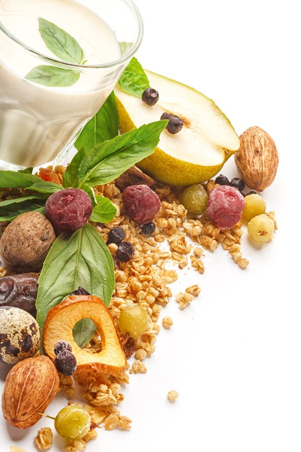 Un bicchiere di latte e muesli con i frutti ed erbe su un fondo bianco Isolato immagine stock libera da diritti Un bicchiere di latte e muesli con i frutti ed erbe su un fondo bianco Isolato immagine stock libera da diritti