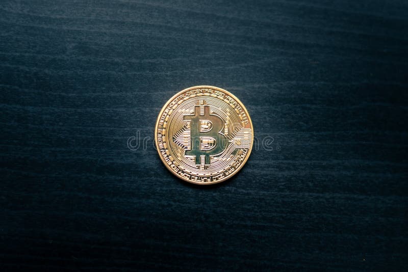 Un bitcoin physique au milieu d'un fond en bois foncé images stock Un bitcoin physique au milieu d'un fond en bois foncé images stock