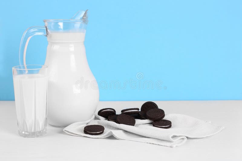 Un broc de lait et de verre de lait avec des biscuits sur une table en bois sur un fond bleu photo stock Un broc de lait et de verre de lait avec des biscuits sur une table en bois sur un fond bleu photo stock