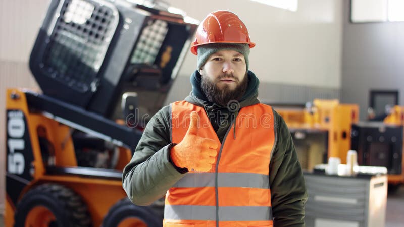 Un buen mec?nico del retrato muestra la aprobaci?n de la muestra, dando los pulgares para arriba el servicio profesional del coch