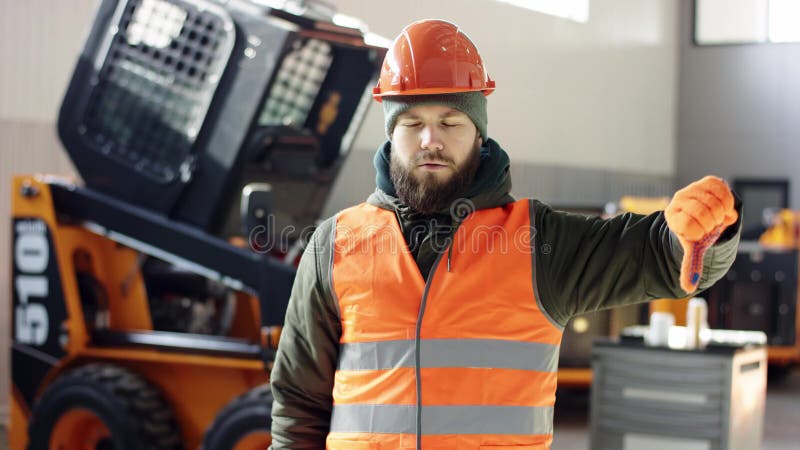 Un buen mec?nico del retrato muestra la desaprobaci?n de la muestra, dando los pulgares abajo el servicio profesional del coche d