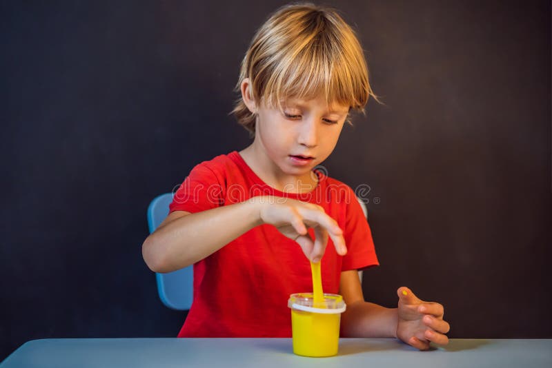 Un băiat care se joacă cu mâna a făcut o jucărie numită slămâie. joacă-te cu copii cu noroi. stoarce și întindere mâzgă stock photo