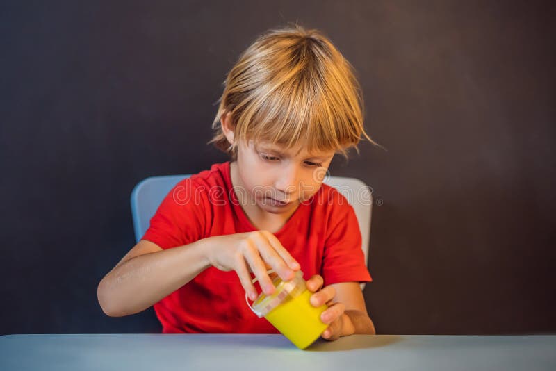 Un băiat care se joacă cu mâna a făcut o jucărie numită slămâie. joacă-te cu copii cu noroi. stoarce și întindere mâzgă stock image