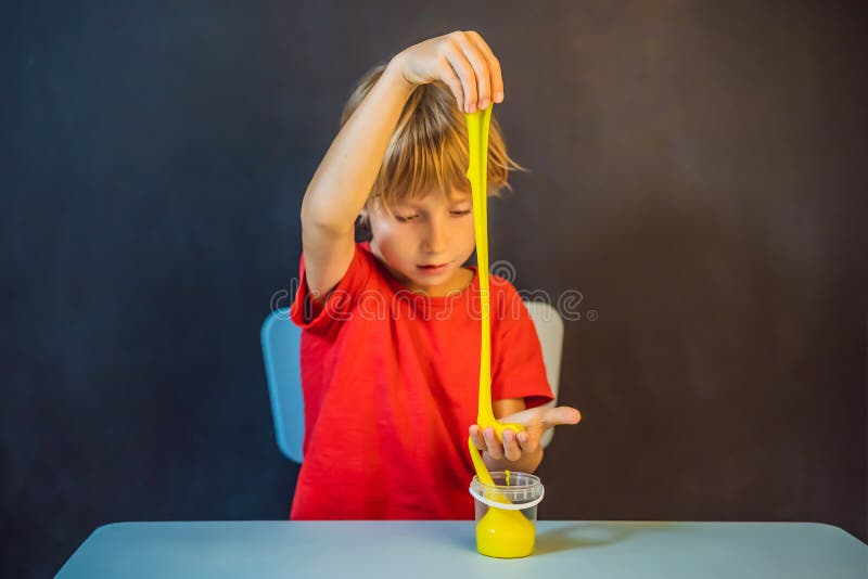 Un băiat care se joacă cu mâna a făcut o jucărie numită slămâie. joacă-te cu copii cu noroi. stoarce și întindere mâzgă royalty free stock photography