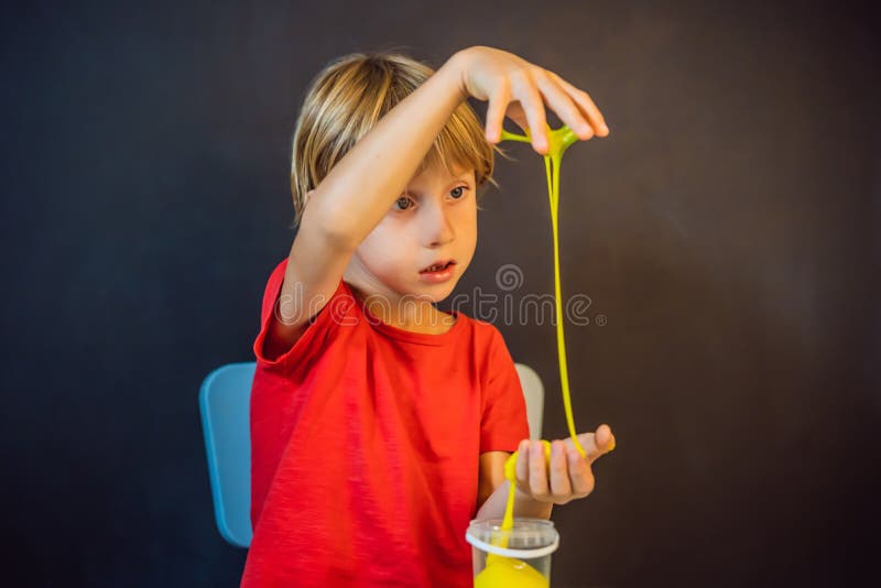 Un băiat care se joacă cu mâna a făcut o jucărie numită slămâie. joacă-te cu copii cu noroi. stoarce și întindere mâzgă royalty free stock image