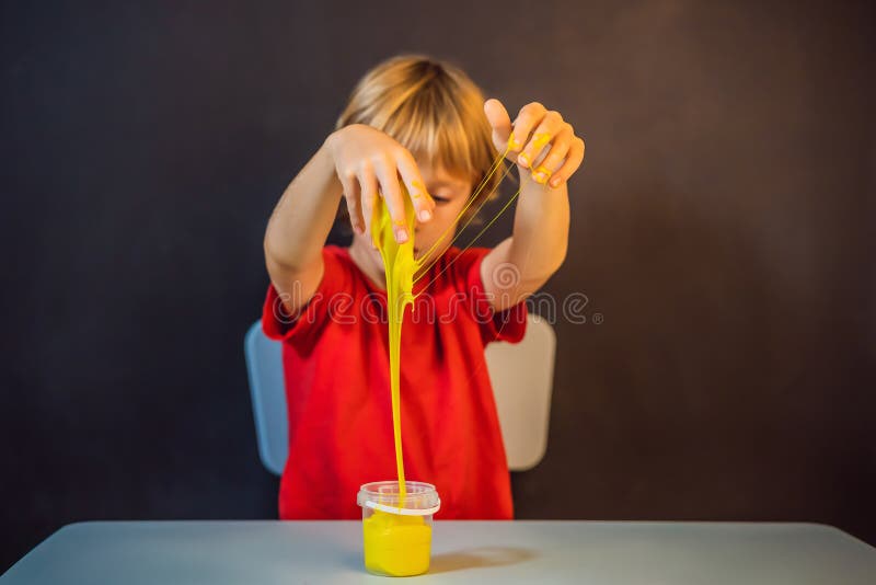 Un băiat care se joacă cu mâna a făcut o jucărie numită slămâie. joacă-te cu copii cu noroi. stoarce și întindere mâzgă royalty free stock photo