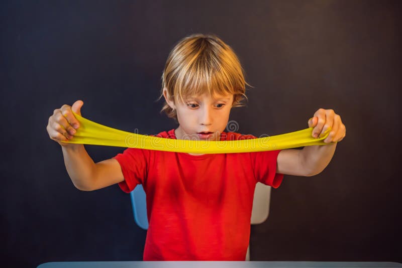 Un băiat care se joacă cu mâna a făcut o jucărie numită slămâie. joacă-te cu copii cu noroi. stoarce și întindere mâzgă royalty free stock image