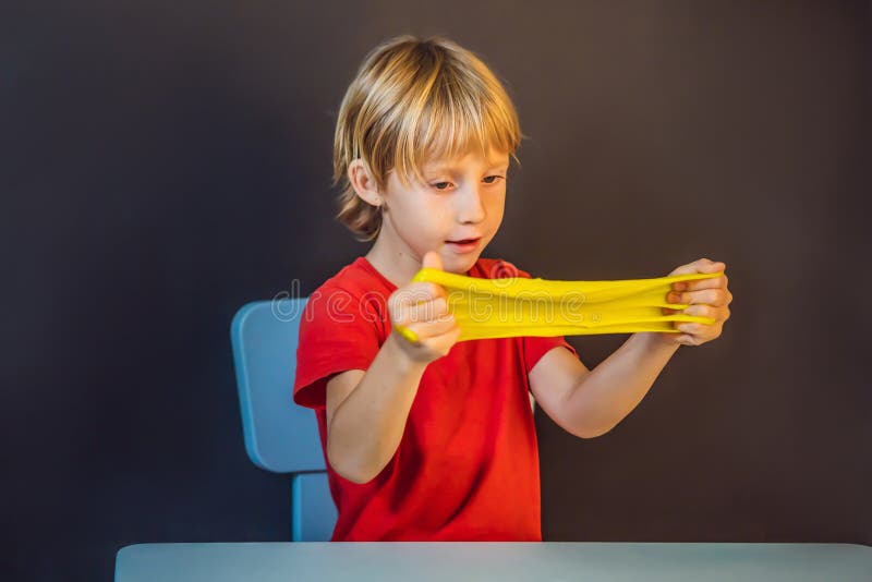 Un băiat care se joacă cu mâna a făcut o jucărie numită slămâie. joacă-te cu copii cu noroi. stoarce și întindere mâzgă royalty free stock images