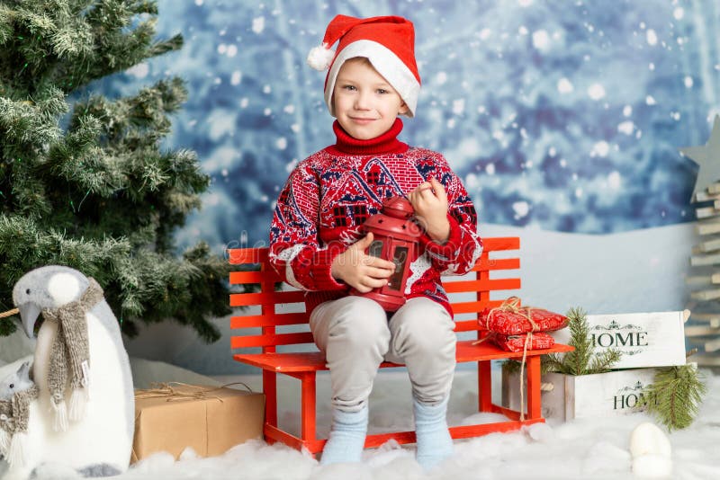 Un băiețel într-o pălărie de Crăciun și un pulover roșu cu un felinar stock photography